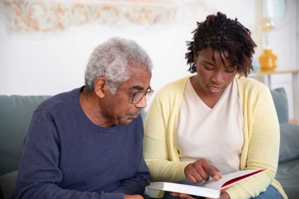 Home care companion reading with an elderly man during an in-home visit